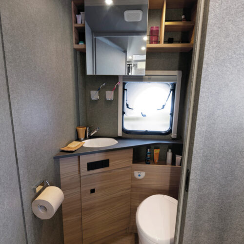 Badkamer met toilet, wastafel, spiegelkastje en raam in Dethleffs Trend I 7027