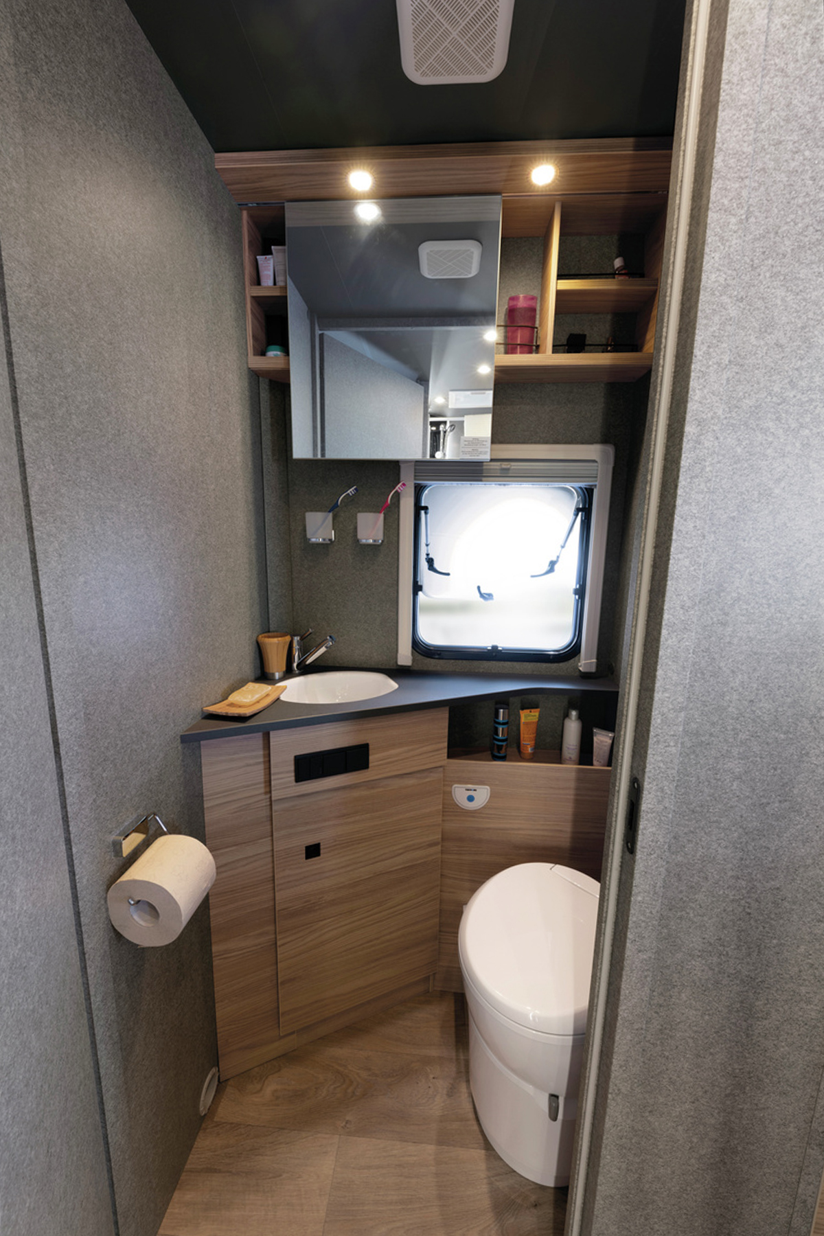Badkamer met toilet, wastafel, spiegelkastje en raam in Dethleffs Trend I 7027