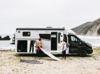 Halfintegraalcamper Sunlight UNLTD 2027 op het strand met twee surfers