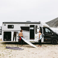 Halfintegraalcamper Sunlight UNLTD 2027 op het strand met twee surfers