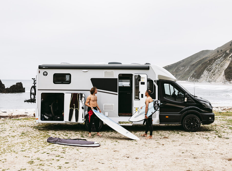 Halfintegraalcamper Sunlight UNLTD 2027 op het strand met twee surfers