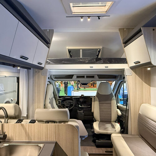 Doorkijkje in de alkoofcamper Sun Living A75 SL 20E met voorin de zitgroep en boven de cabine de alkoof met een tweepersoonsbed van 2,10 meter lang.