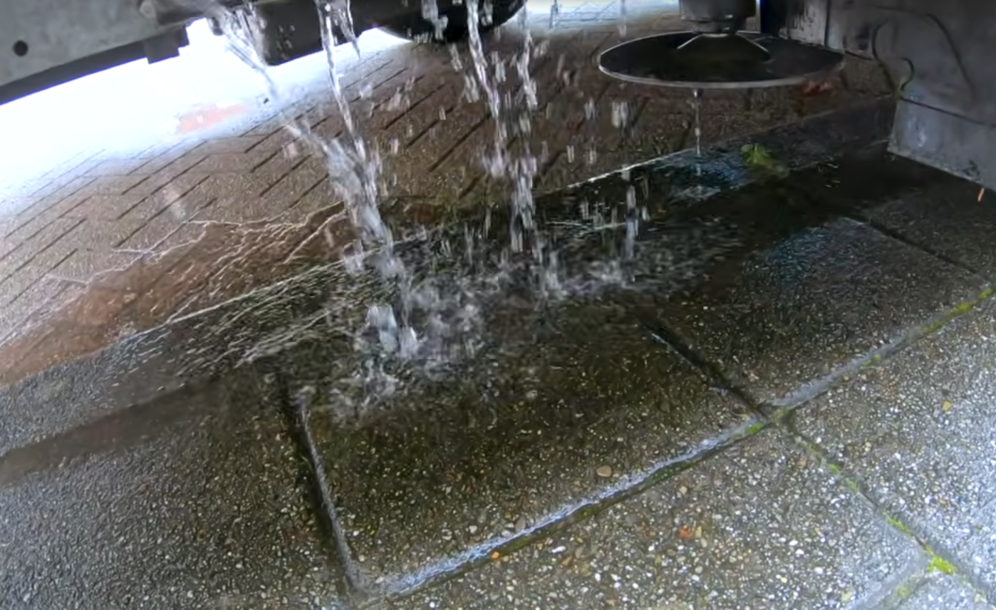 Water uit de tank van een camper loopt weg op straat na openen kraan.
